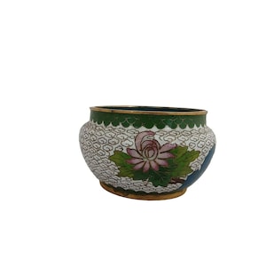 May include: A small, round, white ceramic bowl with a green and blue floral design. The bowl has a gold rim and a white background with a delicate floral pattern.