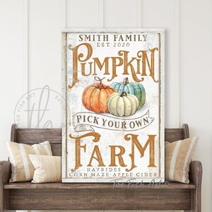May include: A white sign with brown text that reads "Smith Family Est. 2020 Pumpkin Pick Your Own Farm Hayrides Corn Maze Apple Cider". The sign has a rustic look and features three pumpkins in the center.