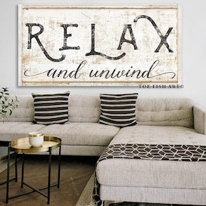 May include: A white wooden sign with black lettering that reads "Relax and unwind" with the text "Toe Fish Art" in the bottom right corner.
