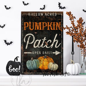 May include: A black and white sign with the text "Hallow Acres Pumpkin Patch Open Daily" in orange and white lettering. The sign is distressed and has a rustic look. There are three pumpkins in the bottom right corner of the sign, one orange, one blue, and one white.