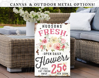 May include: A rectangular sign with a distressed white background featuring the text HUDSONS' FRESH, OPEN DAILY, Flowers, and 25¢ PER STEM. The design includes a central floral arrangement of pink and cream roses with green leaves and stems.