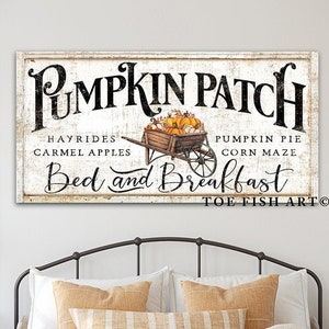 May include: A white sign with black text that reads "Pumpkin Patch" with a drawing of a wheelbarrow full of pumpkins. The sign also says "Hayrides, Carmel Apples, Pumpkin Pie, Corn Maze, Bed and Breakfast, Toe Fish Art".