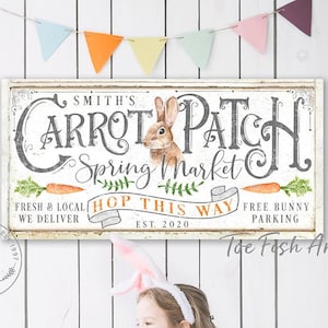 May include: A white sign with the text "Smith's Carrot Patch Spring Market" and a bunny rabbit illustration. The sign also says "Fresh & Local, We Deliver, Hop This Way, Free Bunny Parking, Est. 2020".
