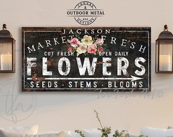 Könnte beinhalten: Ein rechteckiges Wandschild mit einem abgenutzten schwarzen Hintergrund und weißem Text, der Jackson Market Fresh Flowers, Seeds, Stems, Blooms liest. Das Schild zeigt eine zentrale Blumenillustration aus rosa und weißen Rosen und grünen Blättern.