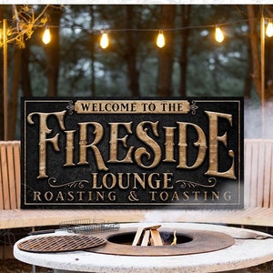 May include: A black metal sign with gold lettering that reads "Welcome to the Fireside Lounge Roasting & Toasting". The sign is hanging above a fire pit with a concrete base and a metal grate. There are wooden benches surrounding the fire pit.