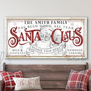 May include: A white wooden sign with red text that reads "The Smith Family Has Been Good All Year Santa Claus Milk & Cookies Please Stop Here Reindeer Parking". The sign features a black and white illustration of Santa Claus and a reindeer.