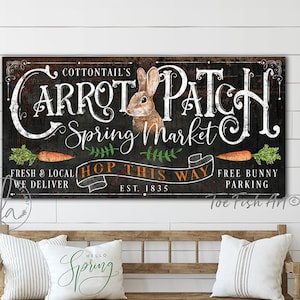 May include: A rustic wooden sign with the text "Cottontail's Carrot Patch Spring Market" in white lettering. The sign also features a cartoon bunny rabbit, carrots, and the text "Hop This Way" with a green leafy design. The sign has a black background and is distressed to give it a vintage look.