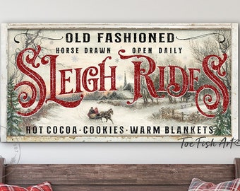 Puede incluir: Un letrero de pared rectangular con una escena invernal de un trineo tirado por caballos y el texto OLD FASHIONED HORSE DRAWN OPEN DAILY SLEIGH RIDES HOT COCOA COOKIES WARM BLANKETS. El letrero tiene un marco blanco desgastado y letras rojas.