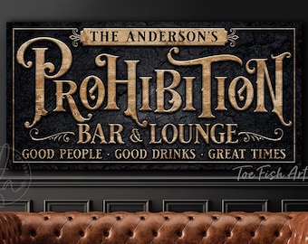 May include: A rectangular wall sign with a black textured background and gold lettering. The text reads THE ANDERSON'S PROHIBITION BAR & LOUNGE, followed by GOOD PEOPLE, GOOD DRINKS, GREAT TIMES. The sign features ornate, vintage-style typography.