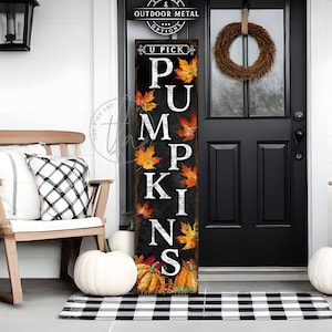 May include: A tall rectangular vertical sign with a dark distressed background featuring the white text U PICK PUMPKINS stacked vertically, accented with colourful autumn maple leaves and illustrations of orange pumpkins at the base.