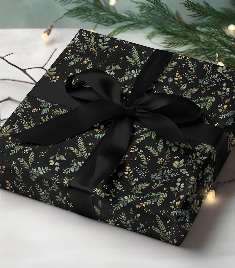 May include: A wrapped gift with black wrapping paper featuring a botanical pattern of green and gold leaves on a black background. A wide black satin ribbon is tied in a bow around the gift.