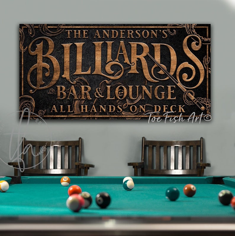 May include: A black and brown wooden sign with the text "The Anderson's Billiards Bar & Lounge All Hands On Deck Toe Fish Art" in a vintage style font.