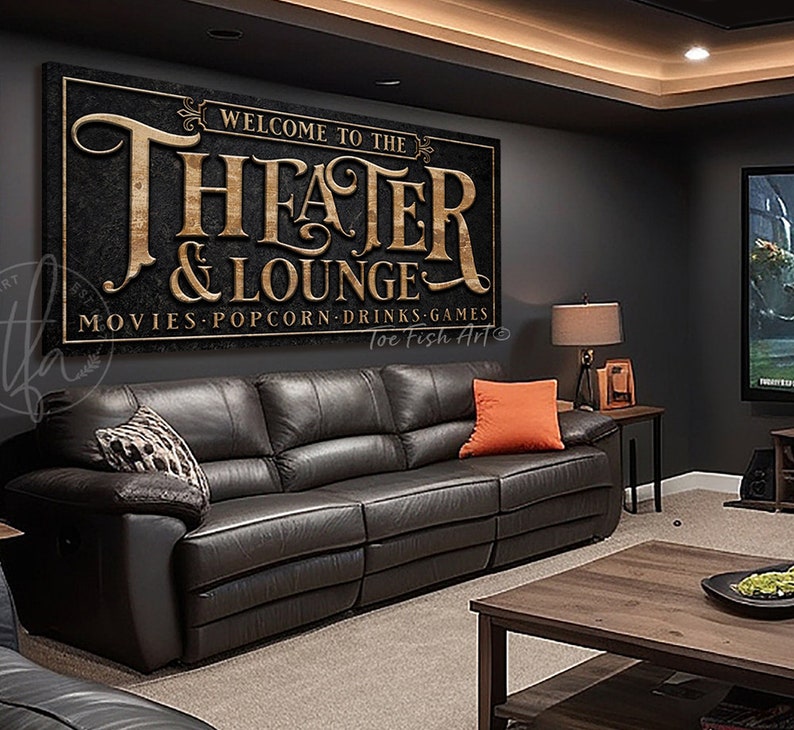 May include: A black and gold sign with the text "Welcome to the Theater & Lounge" and "Movies, Popcorn, Drinks, Games" with the text "Toe Fish Art" at the bottom.