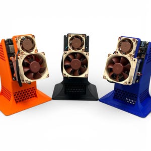 May include: Three cooling stands in orange, black, and blue, each featuring a honeycomb-patterned base and two brown and beige computer fans mounted on a vertical frame. The electronic components are visible on the side of each stand.