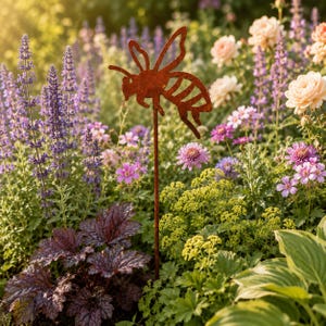 May include: A rust-colored metal garden stake shaped like a flying bee, featuring a cutout silhouette design with defined wings, a segmented body, and antennae, mounted on a thin, straight metal rod for placement in soil.