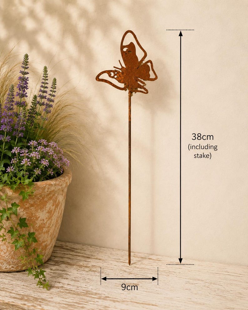 May include: A rust-colored metal butterfly garden stake with a cutout wing design. The total height of the stake is 38 cm, and the width of the butterfly is 9 cm. The metal has a weathered, oxidized finish, and the stake is thin and straight.
