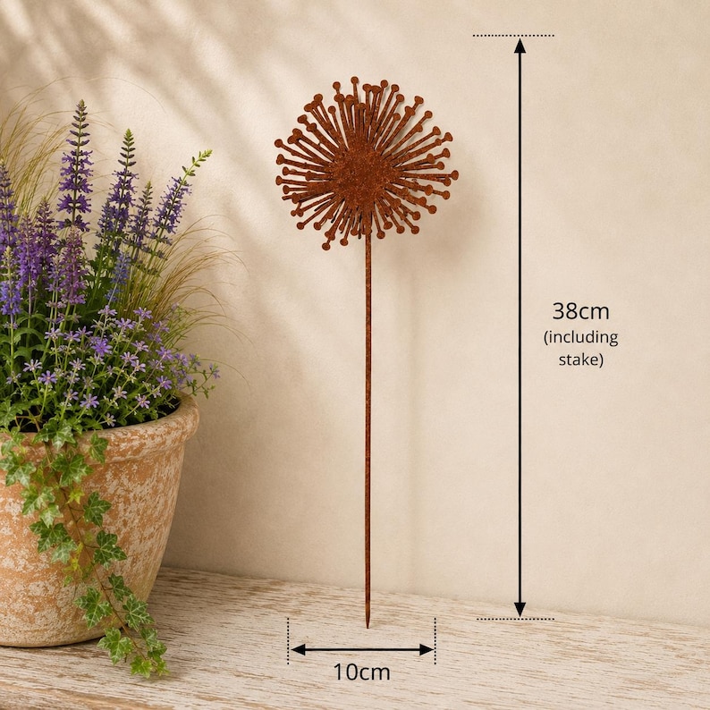 May include: A rust-colored metal garden stake featuring a circular, spiky dandelion-like head. The total height of the decorative piece is 38 cm, including the stake, and the diameter of the circular head is 10 cm. The finish has a textured appearance.