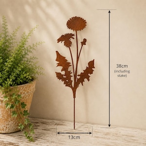 May include: A rust-colored metal garden stake shaped like a dandelion plant with two flower heads and jagged leaves. The item features a total height of 38 cm including the stake and a width of 13 cm, as indicated by the printed text and arrows.
