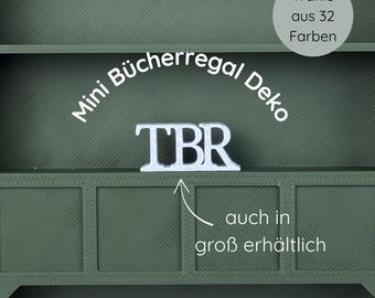 May include: A green decorative shelf with the text "Mini Bücherregal Deko" and "TBR" in white. The shelf has a textured surface and the text "auch in groß erhältlich" is also visible. The image also includes the text "Wähle aus 32 Farben".