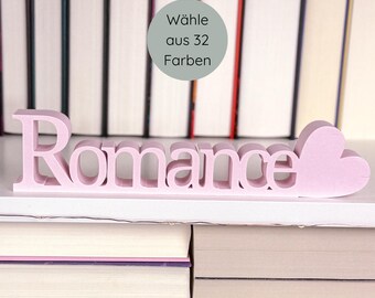 May include: A light pink wooden "Romance" word sign with a heart-shaped design at the end. The sign is displayed on a white shelf in front of a backdrop of books. A circular graphic states "Choose from 32 colors."