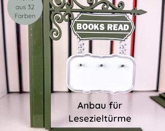 May include: A green metal sign with the text "BOOKS READ" and a blank white sign below it. The sign also has the text "Wähle aus 32 Farben" and "Anbau für Lesezieltürme". The sign is designed to be a bookshelf accessory.