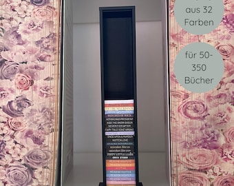 Könnte beinhalten: Ein schwarzer Bücherständer mit einer Reihe bunter Bücher. Der Ständer wird von zwei Buchstützen mit floralem Muster flankiert. Der Text auf dem Bild weist darauf hin, dass der Ständer in 32 Farben erhältlich ist und 50-350 Bücher fasst.