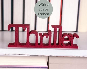 May include: A red wooden "Thriller" word sign, ideal for book lovers. The sign is displayed on a shelf in front of a backdrop of books. A circular graphic in the background reads "Wähle aus 32 Farben".