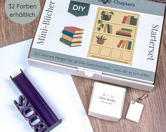 May include: A DIY miniature bookshelf kit with a purple book stand that says "BOOKS". The box includes a starter set, mini-books, and a blank tag. The box has the text "Sculpted Chapters" and "Mini-Bücher".