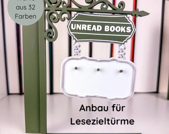 May include: A green metal sign with the text "UNREAD BOOKS" and a blank white sign below. The sign also has the text "Wähle aus 32 Farben" and "Anbau für Lesezieltürme". The sign is designed to be placed in front of books.