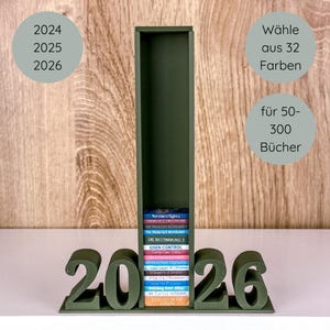 May include: A dark green bookshelf with the numbers 2026 at the base. The bookshelf holds a stack of colourful books. Text on the image includes "2024, 2025, 2026", "Choose from 32 colours", and "for 50-300 books."