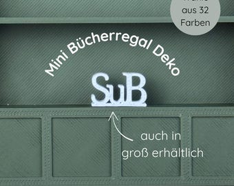 May include: A green decorative shelf with the text "Mini Bücherregal Deko" and the letters "SuB" in white. The text "Wähle aus 32 Farben" is in a circle. The text "auch in groß erhältlich" is also visible.