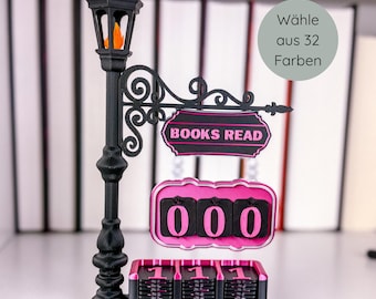 May include: A black decorative lamp post with a sign that reads "BOOKS READ" and a counter displaying "000". The lamp has an orange flame and a pink and black counter. The sign says "Wähle aus 32 Farben".