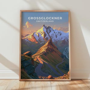 以下が含まれることがあります： 上部にGROSSGLOCKNER SWITZERLANDの文字が記された、山岳風景の縦型フレーム入りアートプリント。夕日の温かい光に照らされた雪を頂いた山頂へと続く曲がりくねった道と、青い空が描かれています。