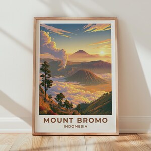 May include: A framed art print featuring a landscape of Mount Bromo in Indonesia at sunrise. The scene displays volcanic peaks rising above a sea of clouds, with golden sunlight, a plume of smoke, and trees in the foreground. The text reads MOUNT BROMO INDONESIA.