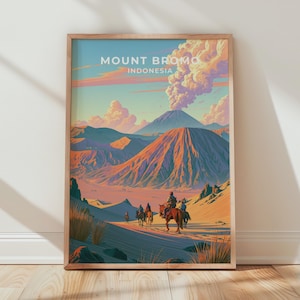 May include: A framed travel poster featuring a stylized illustration of Mount Bromo, Indonesia. The artwork depicts a volcanic landscape with a smoking peak, orange mountains, and a group of people riding horses across a sandy terrain.