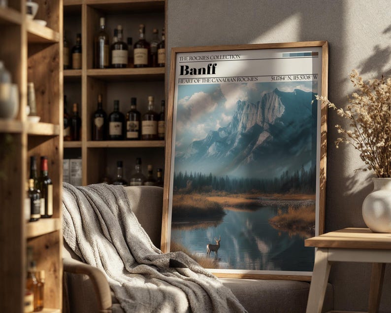 May include: Framed art print of Banff, Heart of the Canadian Rockies, featuring a mountain landscape with a lake and a deer. The print has a wooden frame and includes the coordinates 51.784 N, 115.5708 W.