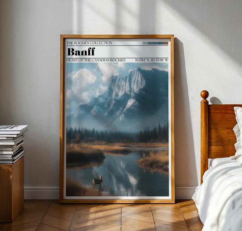 May include: A framed art print featuring a scenic landscape of Banff, part of the Canadian Rockies. The artwork showcases a mountain range reflected in a calm lake, with a deer in the water. The text "Banff" and coordinates are visible.
