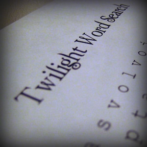 May include: A close-up of a white page with the words "Twilight Word Search" printed in a dark, elegant font. The letters are slightly angled, and other letters are visible in the background.