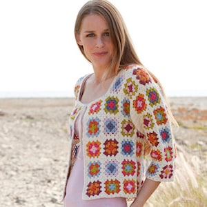 May include: Cream-colored crochet jacket with colorful square patterns. The jacket features a square neckline and three-quarter sleeves. The squares are in shades of pink, orange, blue, green, and yellow.