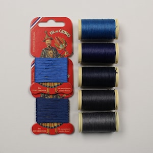 May include: Six spools of waxed thread in shades of blue, from dark to light, labelled "Fil au Chinois" and "Ets Toulemonde".