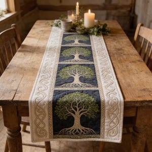 May include: A rectangular table runner featuring a tree of life design. The runner has a black background with green and beige tree imagery. The edges are cream-colored with a beige Celtic knot pattern. Candles and a mug are on the table.