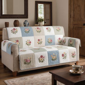 Puede incluir: Un sofá beige con un edredón patchwork floral. El edredón presenta cuadrados bordados en blanco, azul claro y beige, cada uno con un arreglo floral diferente en rosa, amarillo y verde. Las fundas de los brazos coinciden.