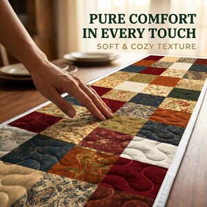 May include: A patchwork table runner in shades of red, blue, beige, and green, with a white border. The image includes the text "PURE COMFORT IN EVERY TOUCH" and "SOFT & COZY TEXTURE". The runner is placed on a wooden table.