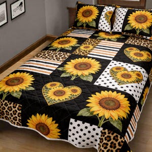 May include: A quilted bedspread and two pillowcases featuring a sunflower design. The quilt has a patchwork pattern with sunflowers, leopard print, stripes, and polka dots. The sunflowers are yellow and brown, set against a black background.