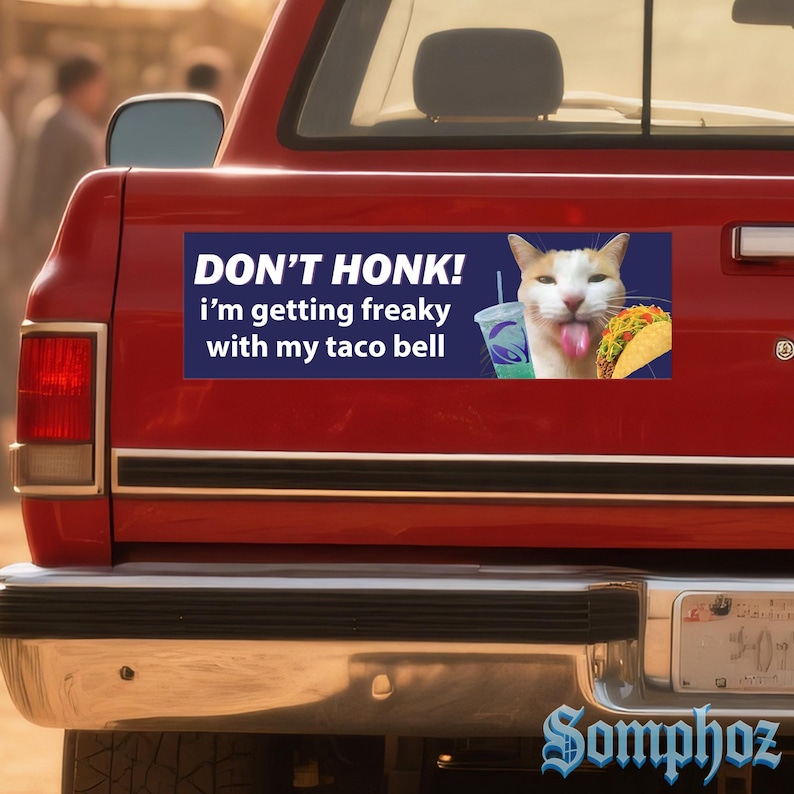 May include: A rectangular bumper sticker on a red truck features a white and orange cat with its tongue out, a Taco Bell drink, and a taco. The text reads "DON'T HONK! I'm getting freaky with my taco bell."