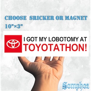 May include: A rectangular bumper sticker or magnet measuring 25.4 cm by 7.6 cm. It features a red square with a white Toyota logo, followed by the black text I GOT MY LOBOTOMY AT and the red text TOYOTATHON! on a white background.