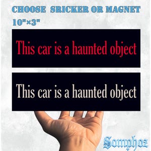 May include: A black rectangular sticker or magnet with the text "This car is a haunted object" in red and white. The sticker measures 25.4 cm x 7.6 cm. The image also includes the text "CHOOSE SRICKER OR MAGNET" in blue.