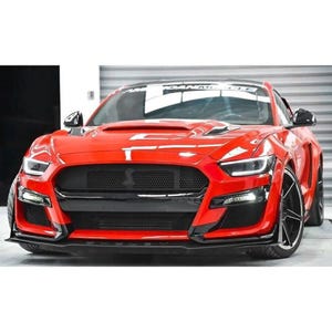 May include: A red Ford Mustang with a black front bumper and grille. The car has a black hood scoop and black side skirts.