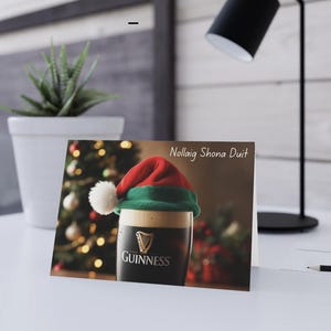 Irisch inspirierte Weihnachtskarte. Pint Guinness trägt eine Weihnachtsmütze.