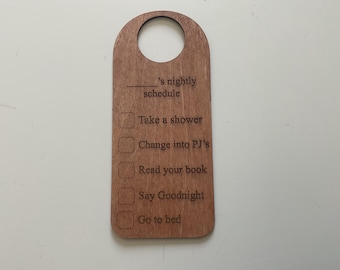 May include: Wooden door hanger with a checklist for a child's nightly routine. The checklist includes "Take a shower", "Change into PJ's", "Read your book", "Say Goodnight", and "Go to bed".